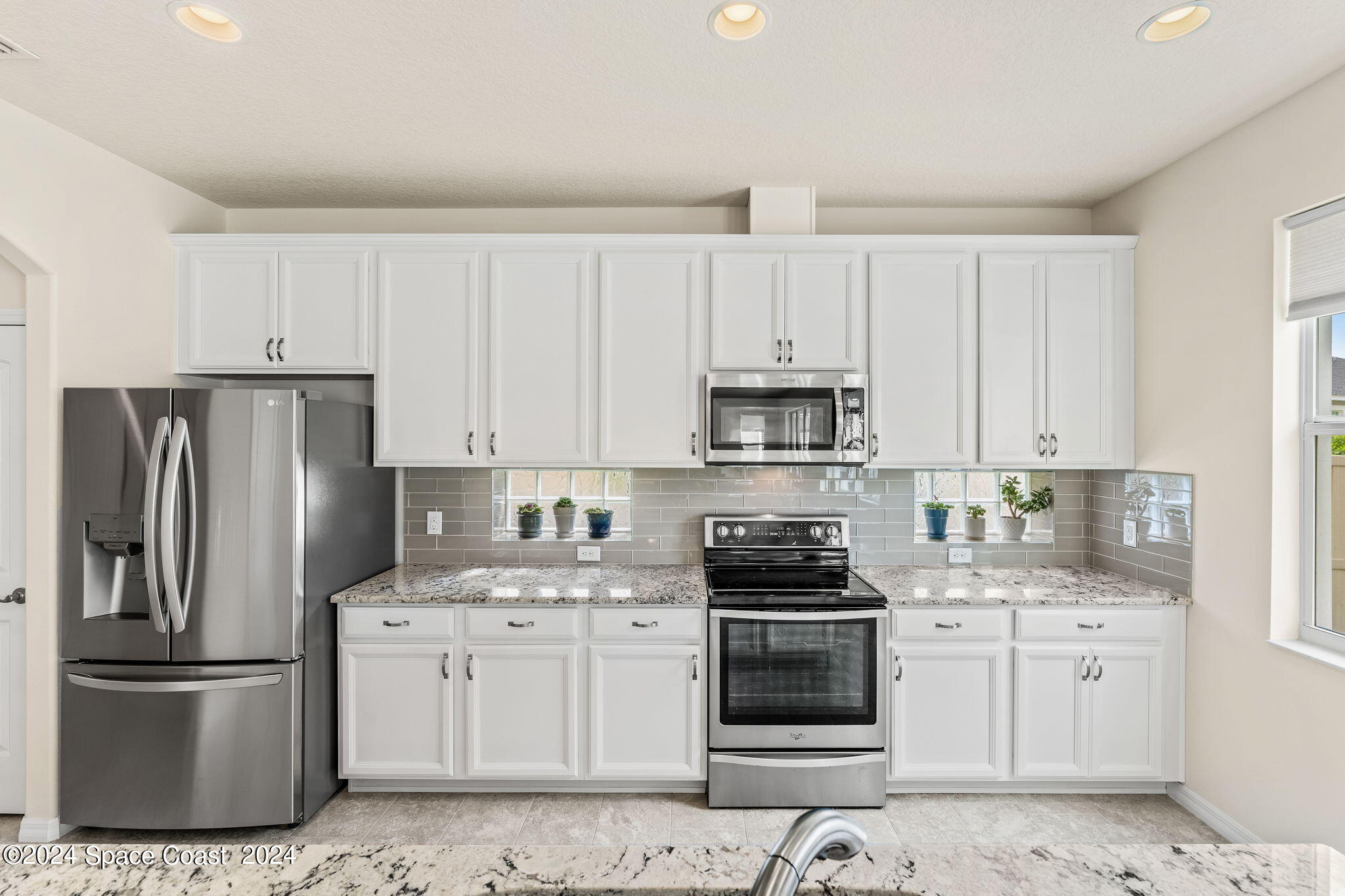 2850 Amethyst Way Melbourne, FL 32940 - Photo 9 of 37 a kitchen with white cabinets and stainless steel appliances