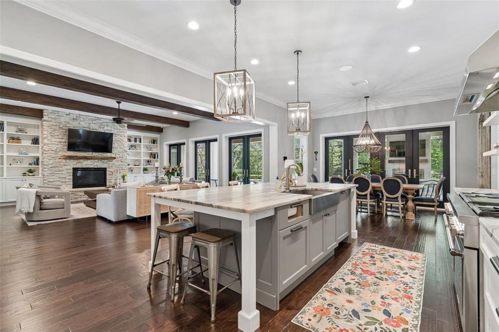 17001 Midas Lane Lutz, FL 33549 - Photo 20 of 100 a large kitchen with kitchen island a stove a chandelier a dining table and chairs with wooden floor