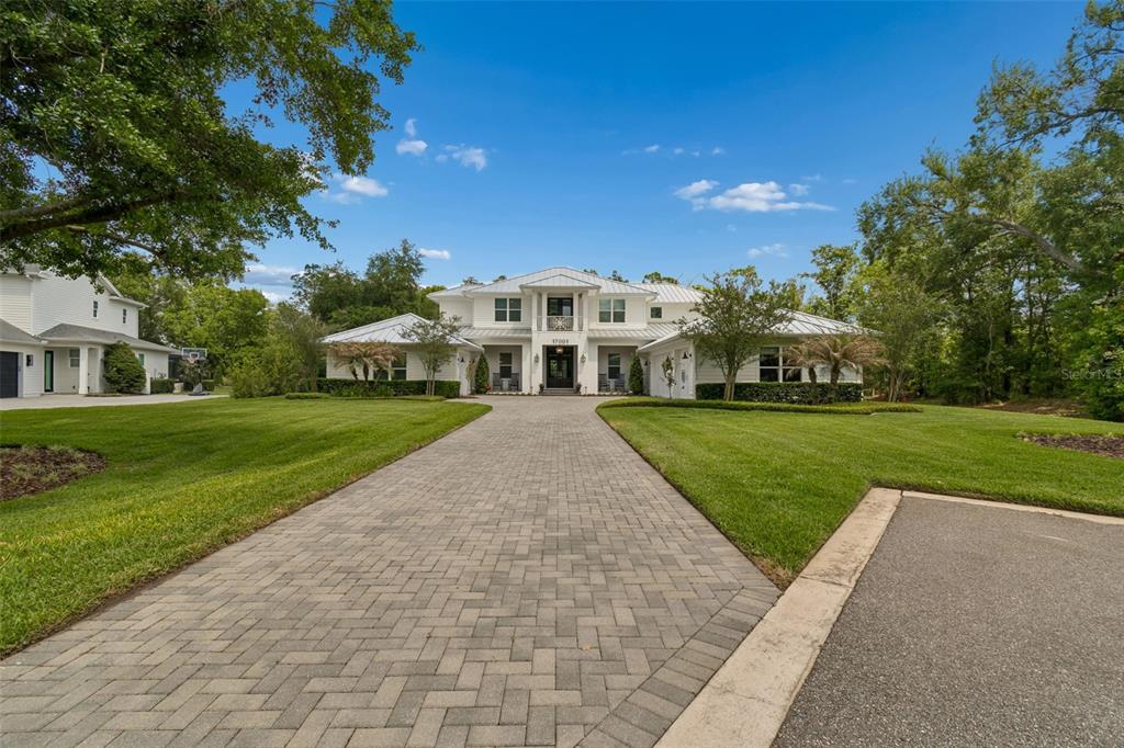 17001 Midas Lane Lutz, FL 33549 - Photo 3 of 100 a view of a white house with a big yard and potted plants and large trees