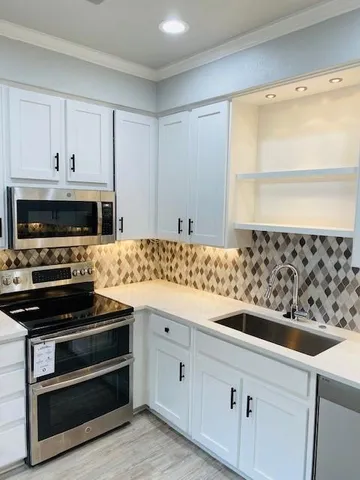a kitchen with granite countertop white cabinets and stainless steel appliances