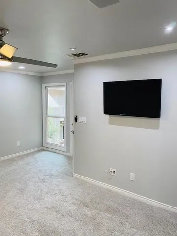 a view of an empty room with a tv and a window
