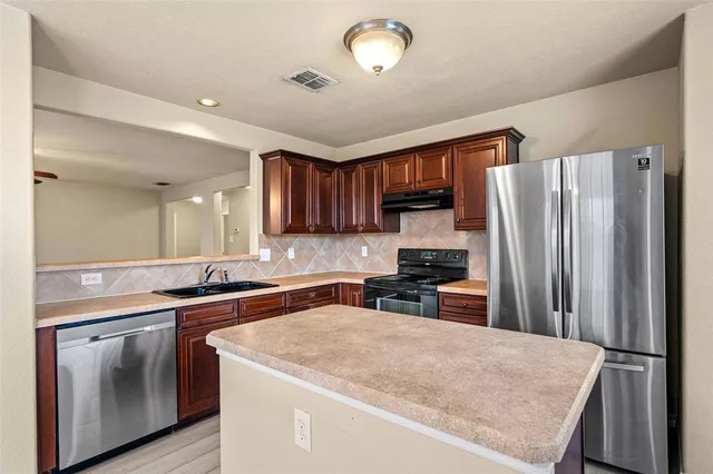 a kitchen with stainless steel appliances granite countertop a refrigerator stove sink and cabinets