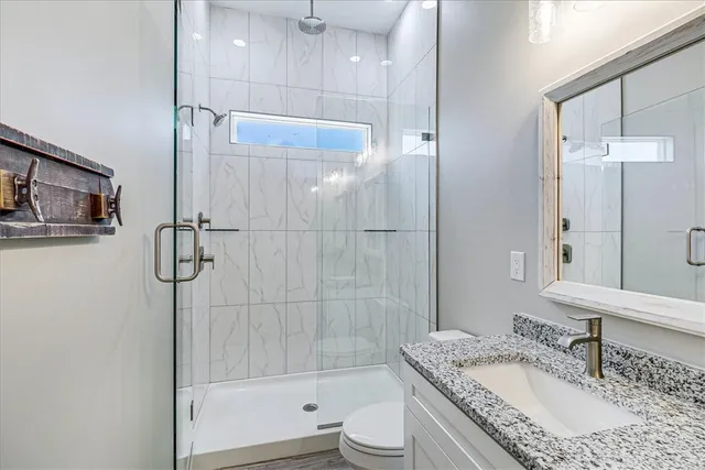 a bathroom with a granite countertop tub sink toilet and shower