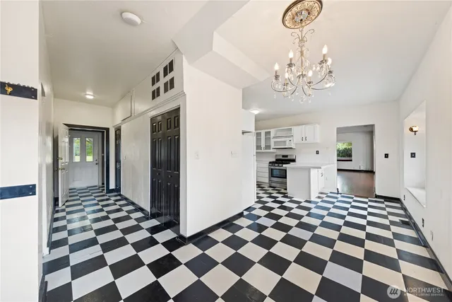 a living room with a black white checkered floor with couches and dinning table with wooden floor
