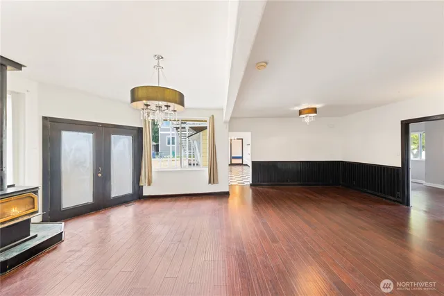 a view of an empty room with window and wooden floor