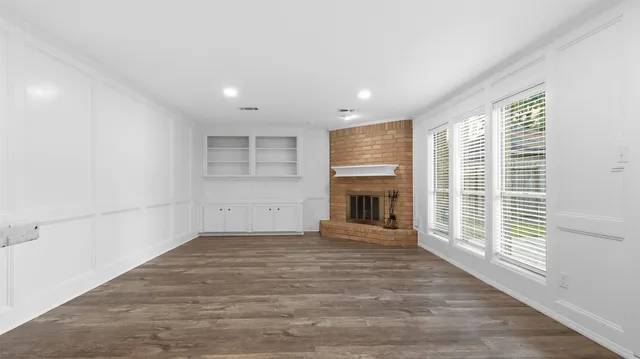 a view of empty room with wooden floor and fireplace