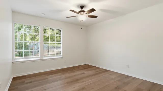an empty room with a chandelier fan and windows