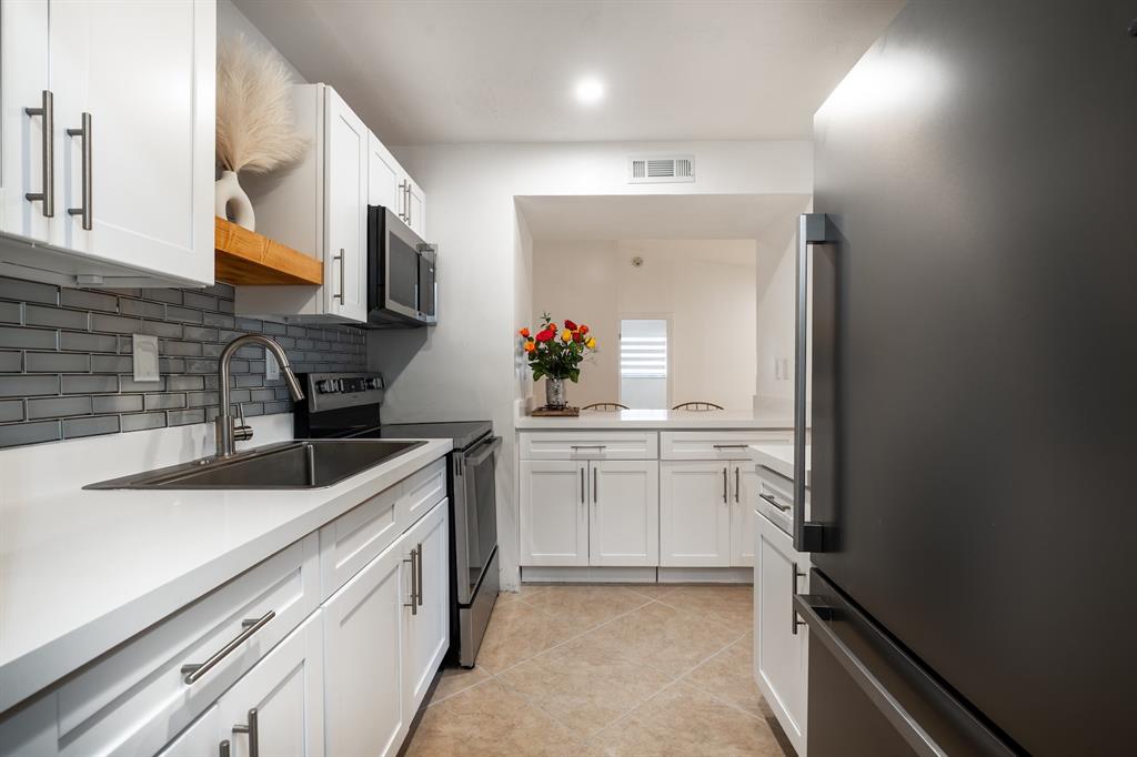 927 Northeast 199th Street, Unit 202 Miami, FL 33179 - Photo 24 of 39 a kitchen with a sink dishwasher stove and cabinets
