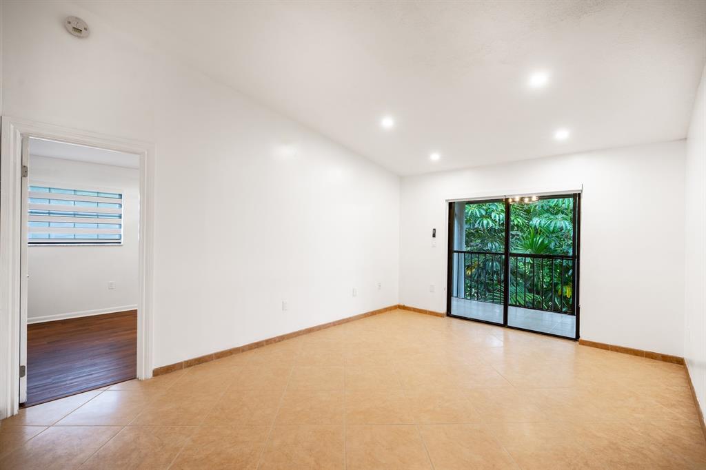 927 Northeast 199th Street, Unit 202 Miami, FL 33179 - Photo 3 of 39 an empty room with wooden floor and windows