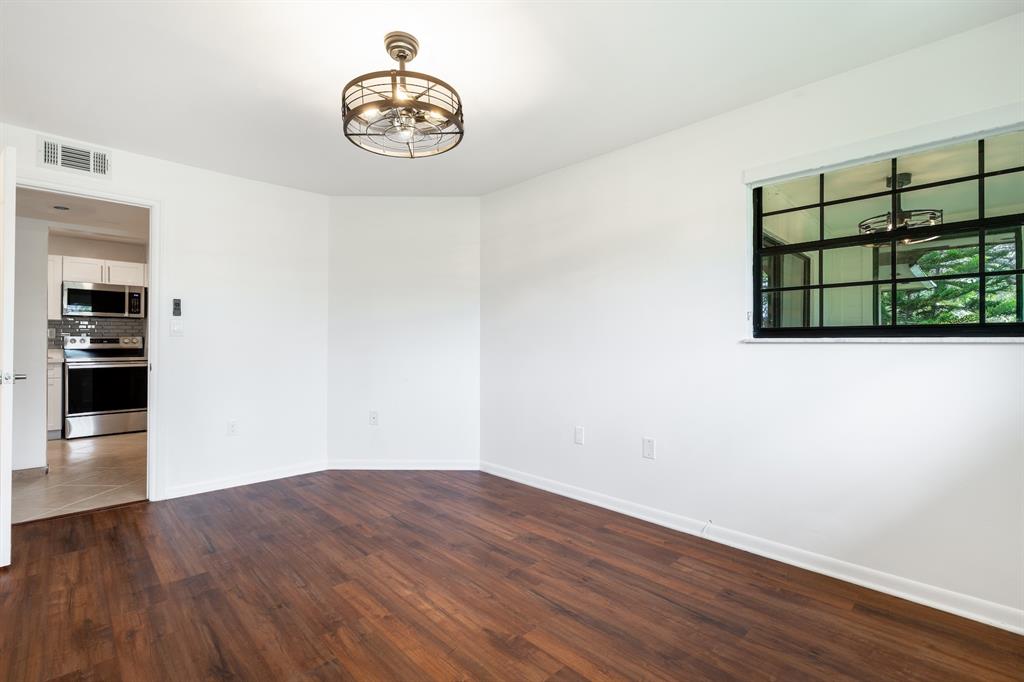 927 Northeast 199th Street, Unit 202 Miami, FL 33179 - Photo 37 of 39 a view of a room with wooden floor and white walls