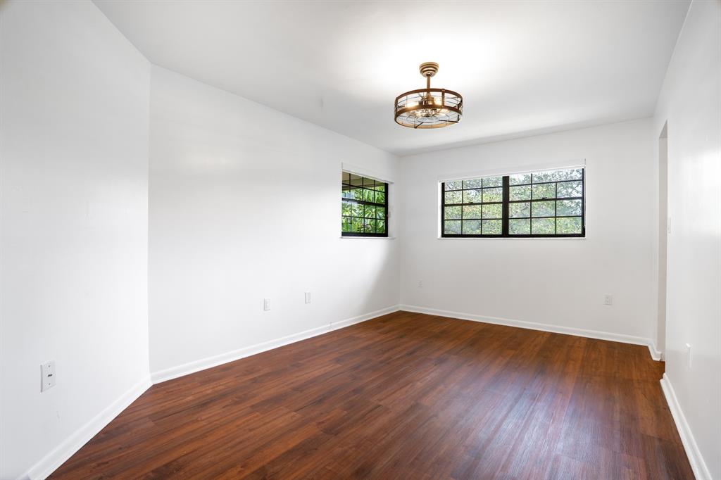 927 Northeast 199th Street, Unit 202 Miami, FL 33179 - Photo 8 of 39 an empty room with wooden floor chandelier fan and windows