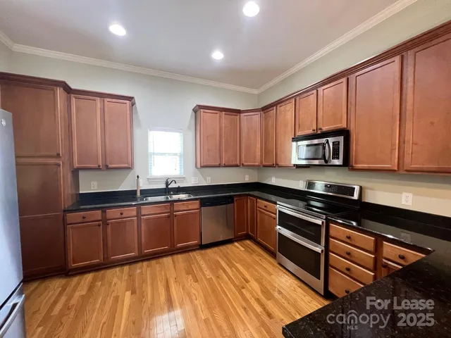 a kitchen with stainless steel appliances granite countertop wooden cabinets a stove top oven a sink and dishwasher