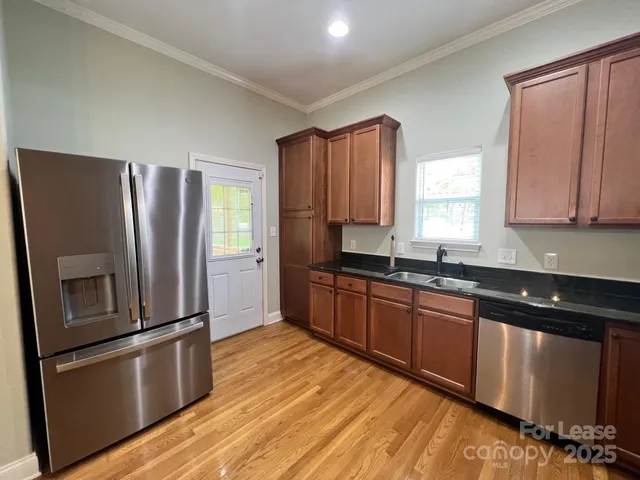 a kitchen with stainless steel appliances granite countertop a refrigerator a sink wooden cabinets and a granite counter tops