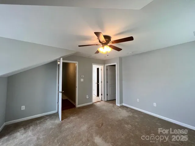 an empty room with closet and a chandelier fan