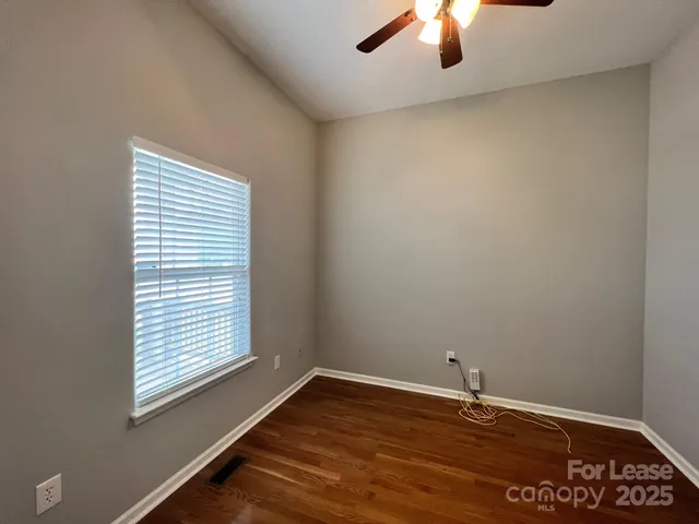 a view of an empty room with window and chandelier fan