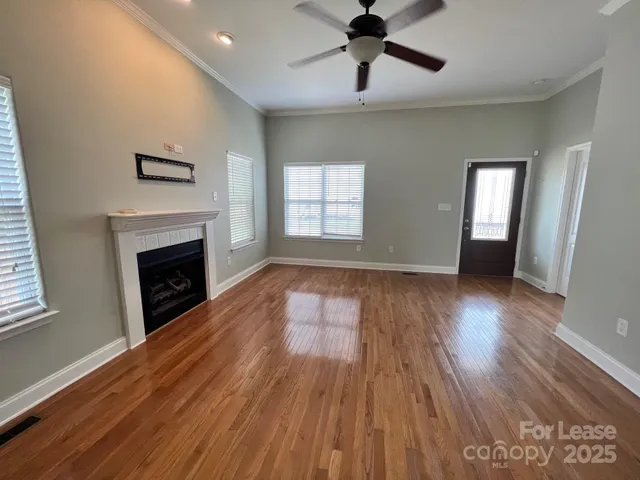 a view of an empty room with wooden floor fireplace and a window