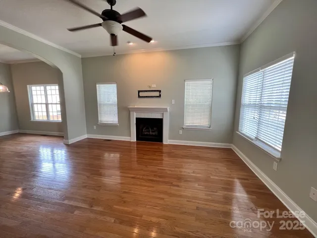 a view of an empty room with window and wooden floor