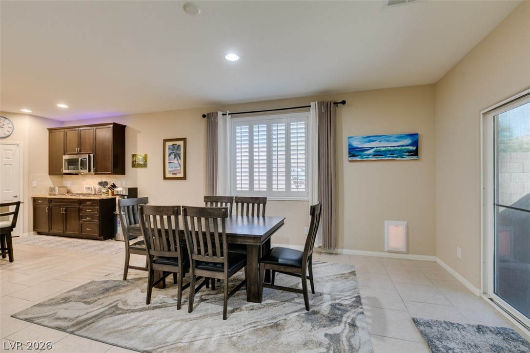 7375 Campbell Ranch Avenue Las Vegas, NV 89179 - Photo 17 of 45 A well-appointed kitchen and dining area features sleek dark cabinetry, modern appliances, and a window with plantation shutters.
