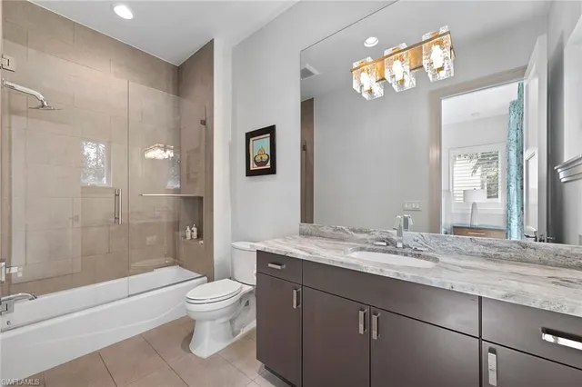 a bathroom with a granite countertop sink toilet a large mirror a bathtub and shower