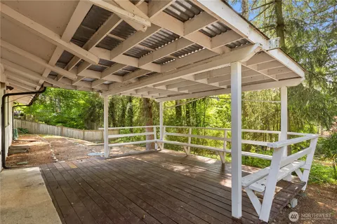 a view of a deck with wooden floor and roof with a small garden