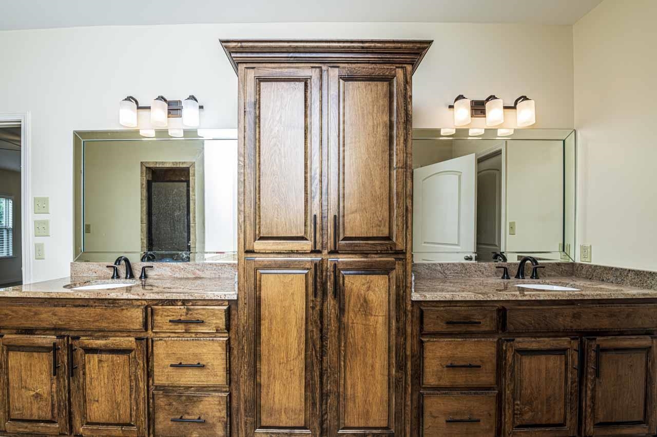 185 Belmont Road Mason, TN 38049 - Photo 14 of 38 Dual wood-finish vanities with undermount sinks, stone countertops, and bronze-finish faucets