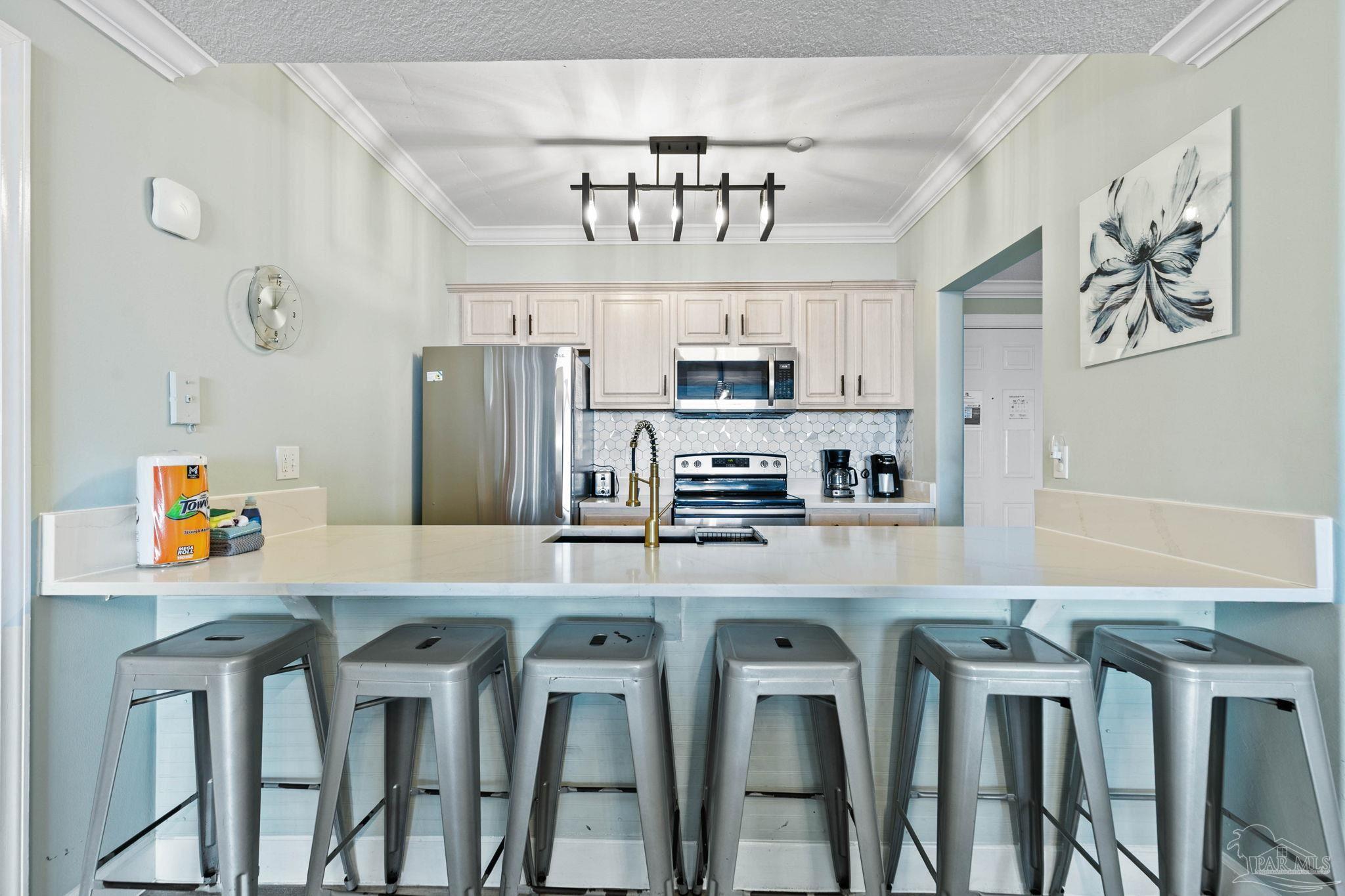 10611 Front Beach Road, Unit 1303 Panama City Beach, FL 32408 - Photo 21 of 71 a kitchen with stainless steel appliances granite countertop a dining table chairs refrigerator and microwave