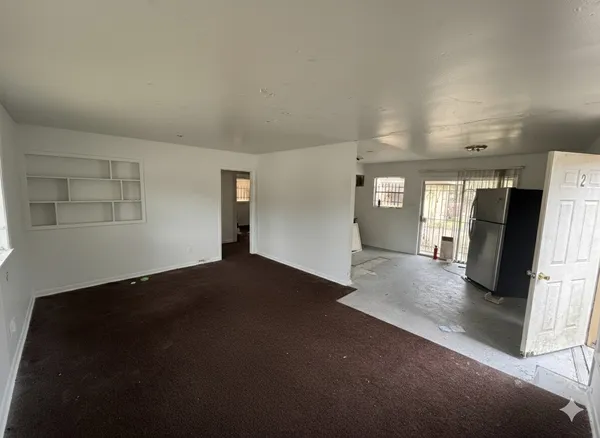 a view of an empty room and a kitchen
