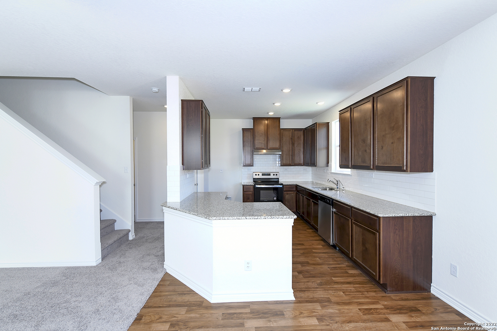 6511 Runaway Row Converse, TX 78109 - Photo 12 of 42 a kitchen with stainless steel appliances a sink a stove a refrigerator cabinets and a wooden floor
