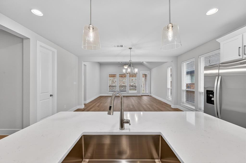 4123 Windy Point Court Oak Point, TX 75068 - Photo 18 of 29 Kitchen island featuring a stainless steel undermount sink, gooseneck faucet, and white countertop