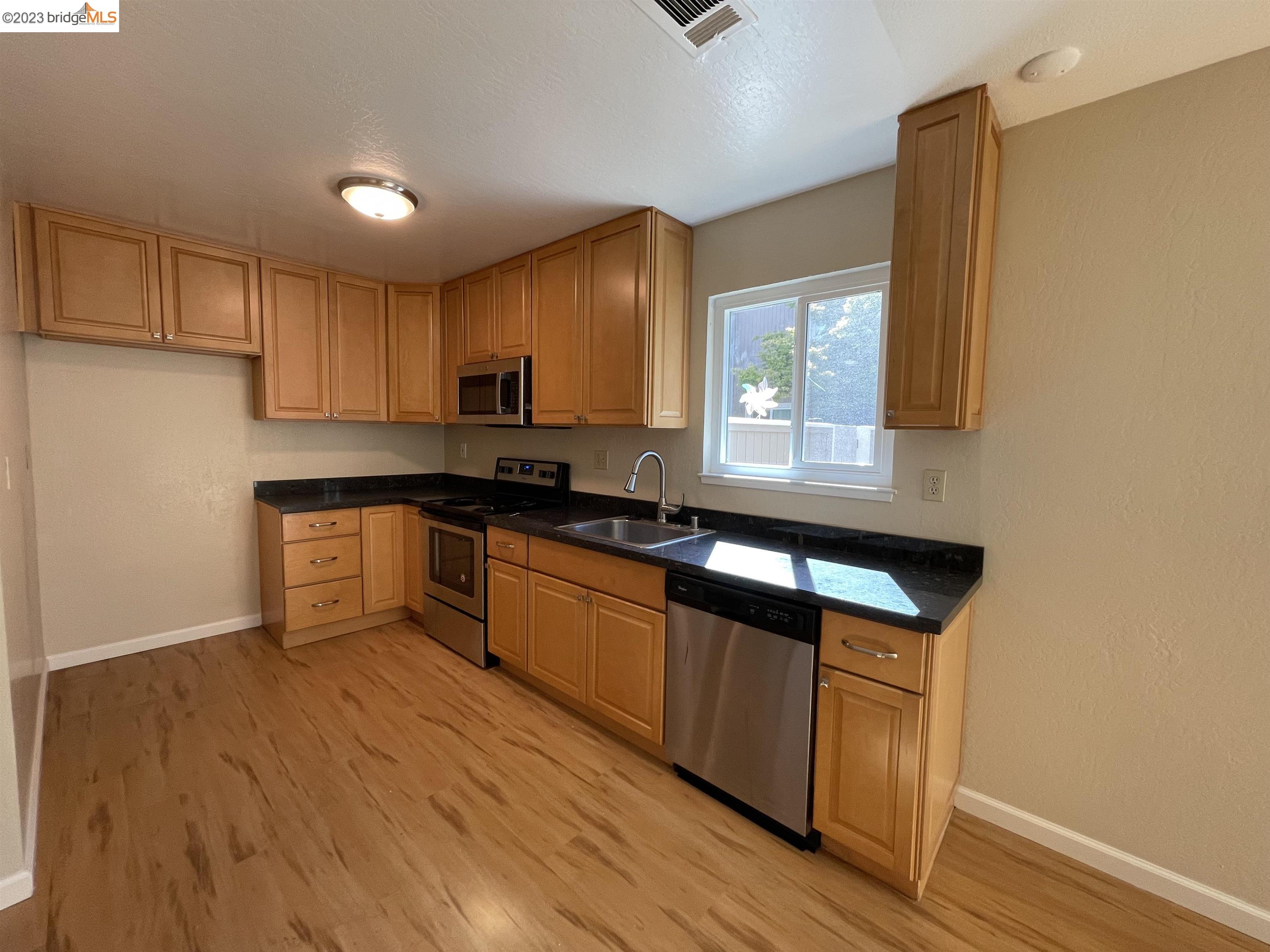 3901 Clayton Road, Unit 57 Concord, CA 94521 - Photo 9 of 40 a kitchen with granite countertop wooden floors a stove and a microwave