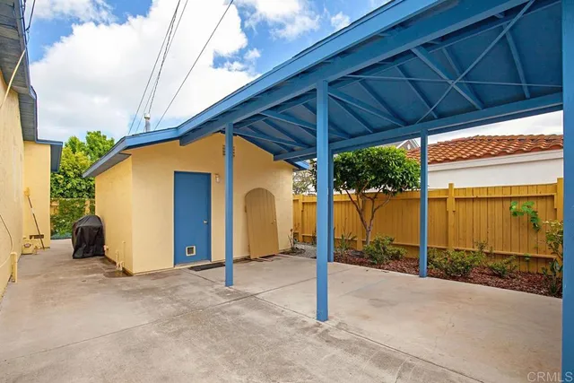 a backyard of a house with a table and chairs under an umbrella