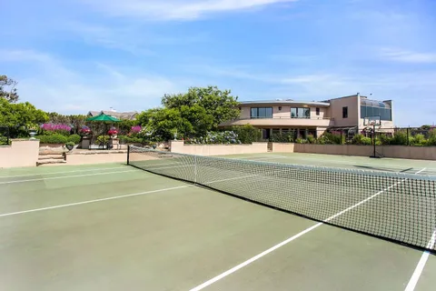 a view of a tennis ground with large trees