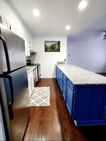 a large kitchen with wooden floor and stainless steel appliances