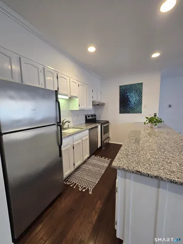 a kitchen with granite countertop a refrigerator and a sink