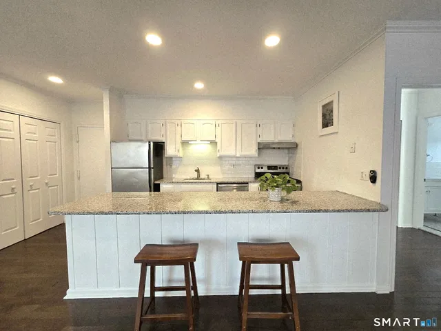 a kitchen with granite countertop white cabinets and stainless steel appliances