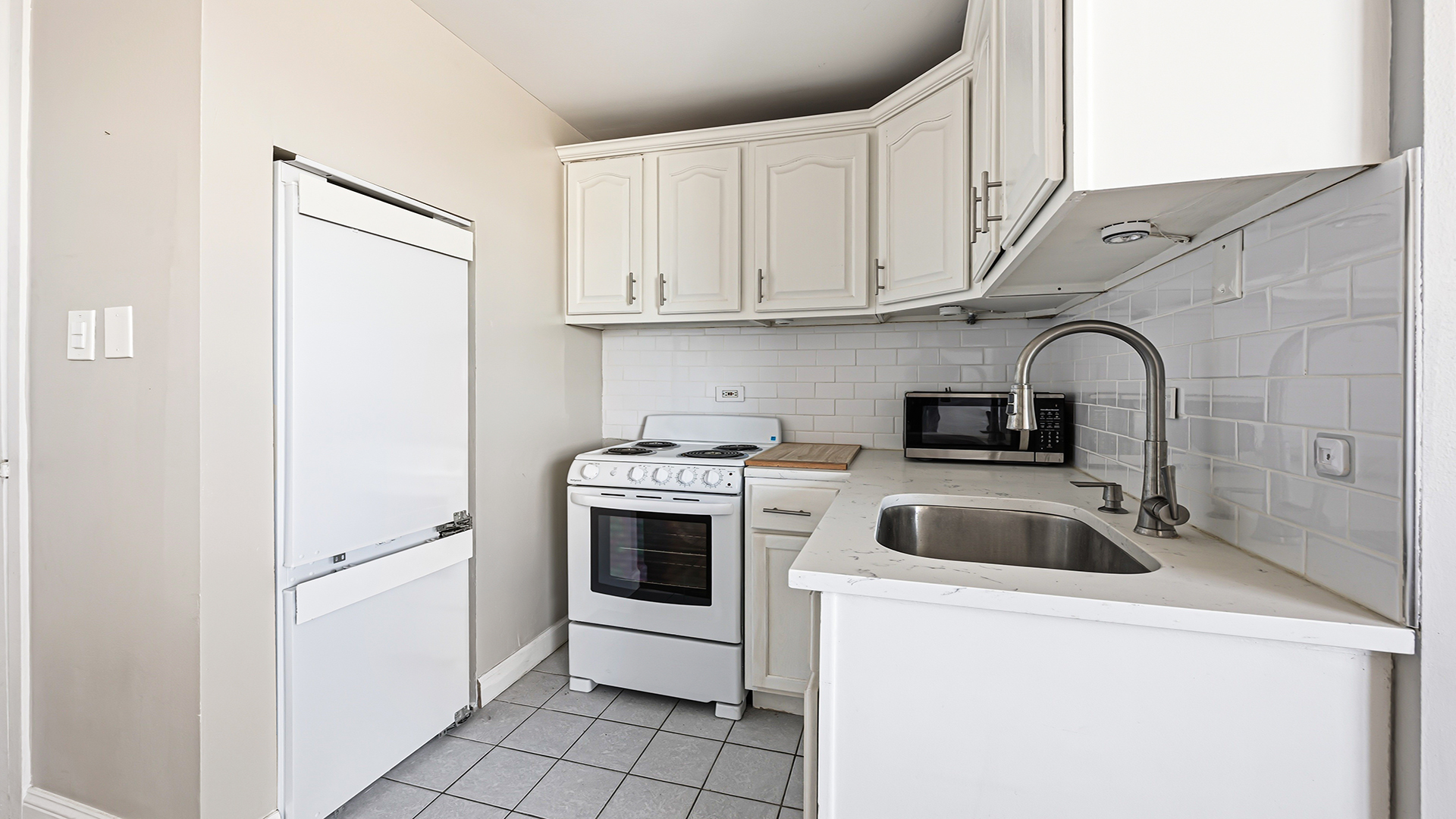 3110 North Sheridan Road, Unit 1807 Chicago, IL 60657 - Photo 10 of 21 a kitchen with white cabinets and white appliances