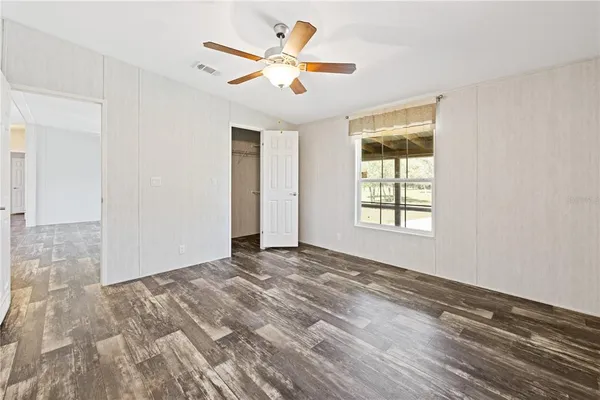 a view of an empty room with window and a ceiling fan