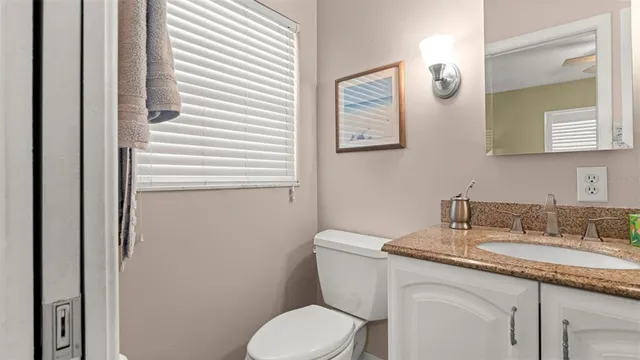 a bathroom with a granite countertop toilet sink and mirror