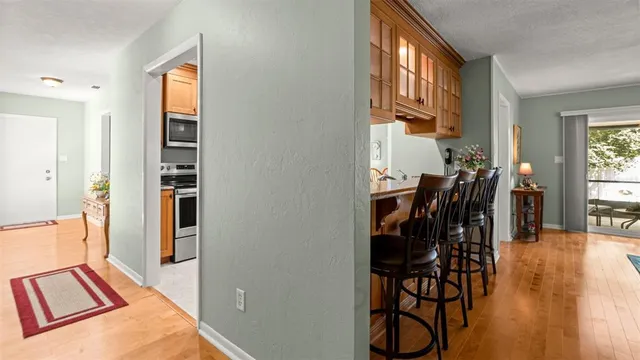 a view of a hallway to room with wooden floor and windows