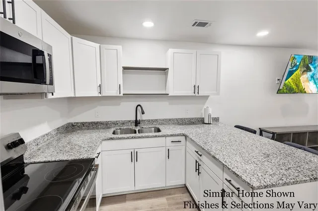 a kitchen with stainless steel appliances granite countertop a sink stove and cabinets