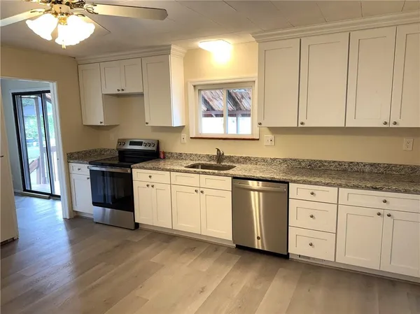 a kitchen with granite countertop white cabinets and wooden floor