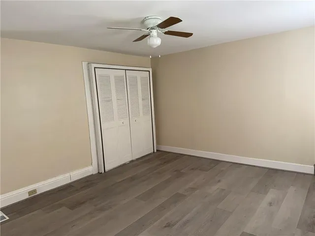 an empty room with wooden floor ceiling fan and window