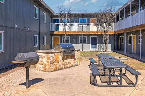 a backyard of a house with barbeque oven table and chairs