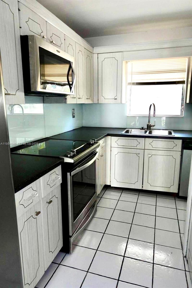 2501 South Ocean Boulevard, Unit 1040 Boca Raton, FL 33432 - Photo 9 of 16 a kitchen with stainless steel appliances a stove microwave and sink