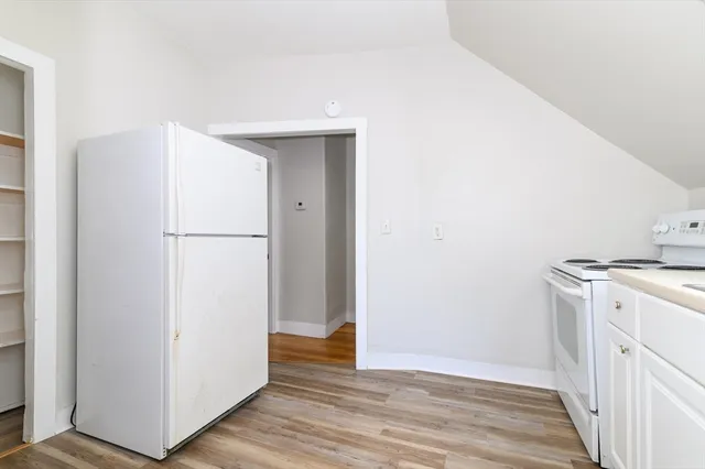 a view of a kitchen with a sink refrigerator and wooden floor