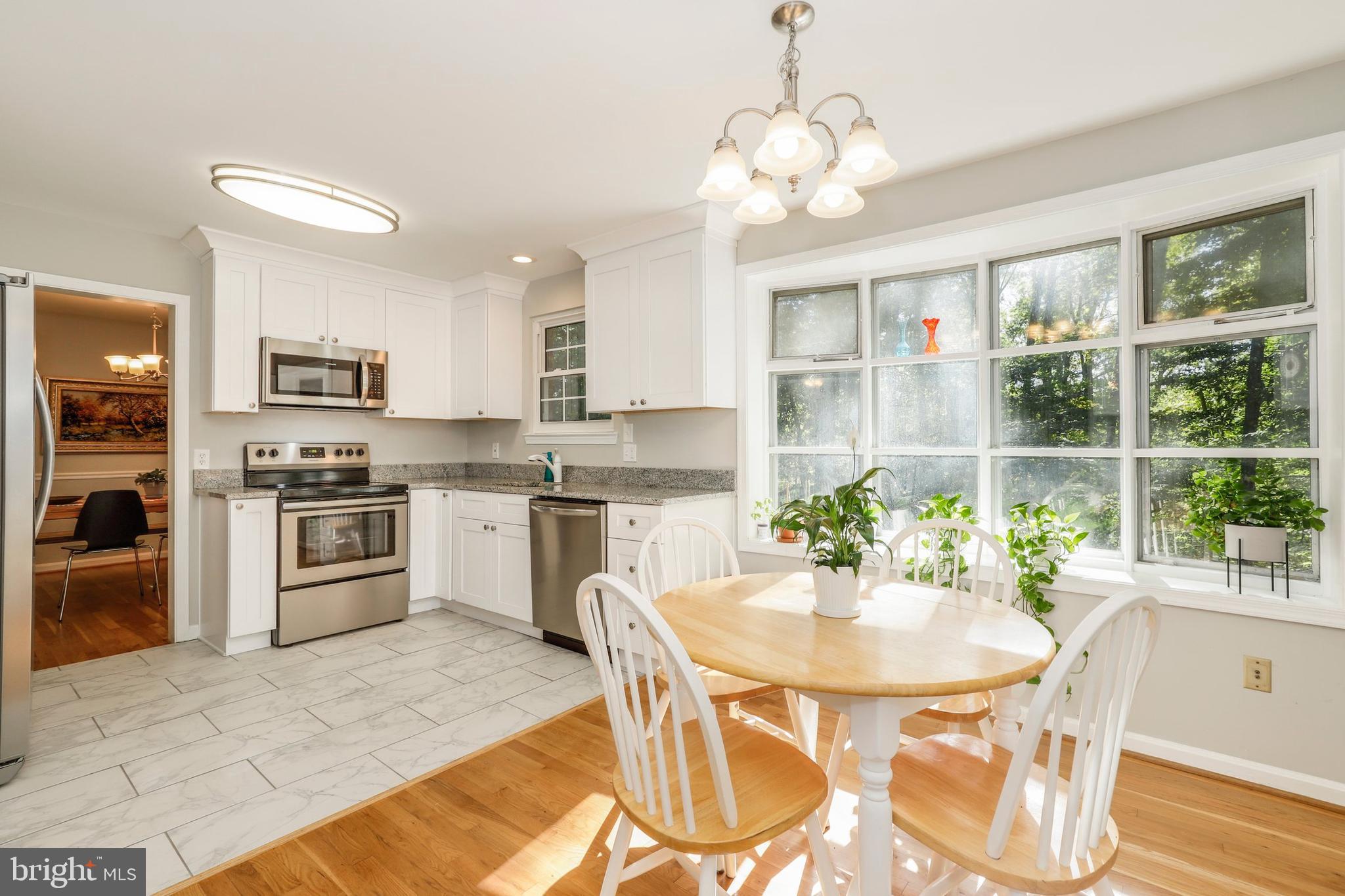 8461 Thames Street Springfield, VA 22151 - Photo 11 of 57 a kitchen with stainless steel appliances granite countertop a stove a sink a microwave a dining table and chairs