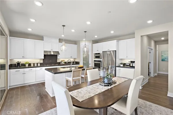 a living room with furniture kitchen view and a wooden floor