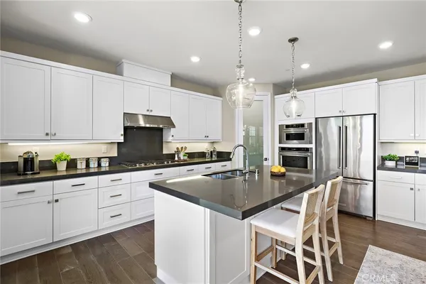 a kitchen with stainless steel appliances kitchen island granite countertop a stove a refrigerator and a dining table with wooden floor