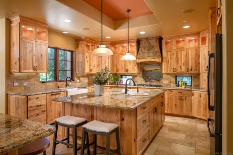 a large kitchen with a large counter top a sink stainless steel appliances and cabinets