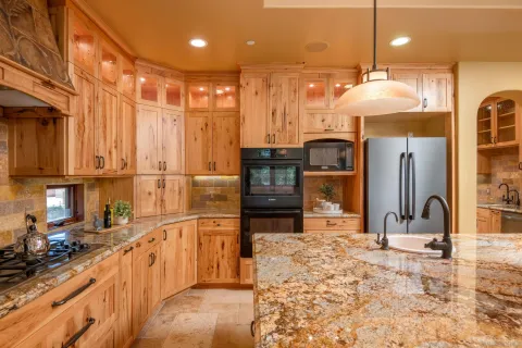 a kitchen with stainless steel appliances kitchen island granite countertop a refrigerator a stove and a sink with granite countertops